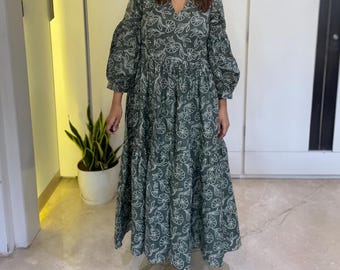 May include: A green maxi dress with a white floral print and puff sleeves.