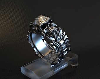 May include: A silver skull ring with intricate mechanical details. The skull has a detailed face and is surrounded by gears and pipes.
