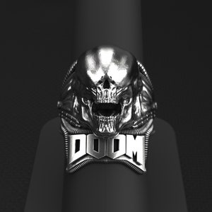 May include: A silver ring with a skull design and the word "DOOM" written below it.