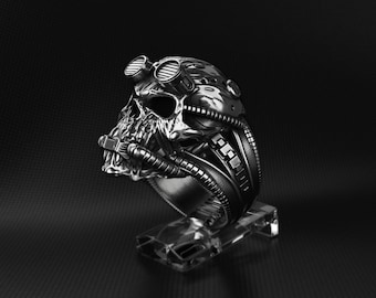 May include: A silver ring with a skull design and a steampunk-inspired helmet. The ring is detailed with goggles, pipes, and gears.