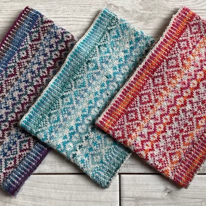 Op de afbeelding: Drie gebreide hoofdbanden in verschillende kleurencombinaties. De hoofdbanden hebben een geometrisch patroon in tinten blauw, turquoise en oranje.