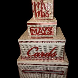 Puede incluir: Un juego de cajas de tarjetas de boda apiladas con una textura tejida beige, adornadas con pedrer&iacute;a roja. La caja superior dice "Mr & Mrs", la caja del medio "MAYS" y la caja m&aacute;s grande "Cards".