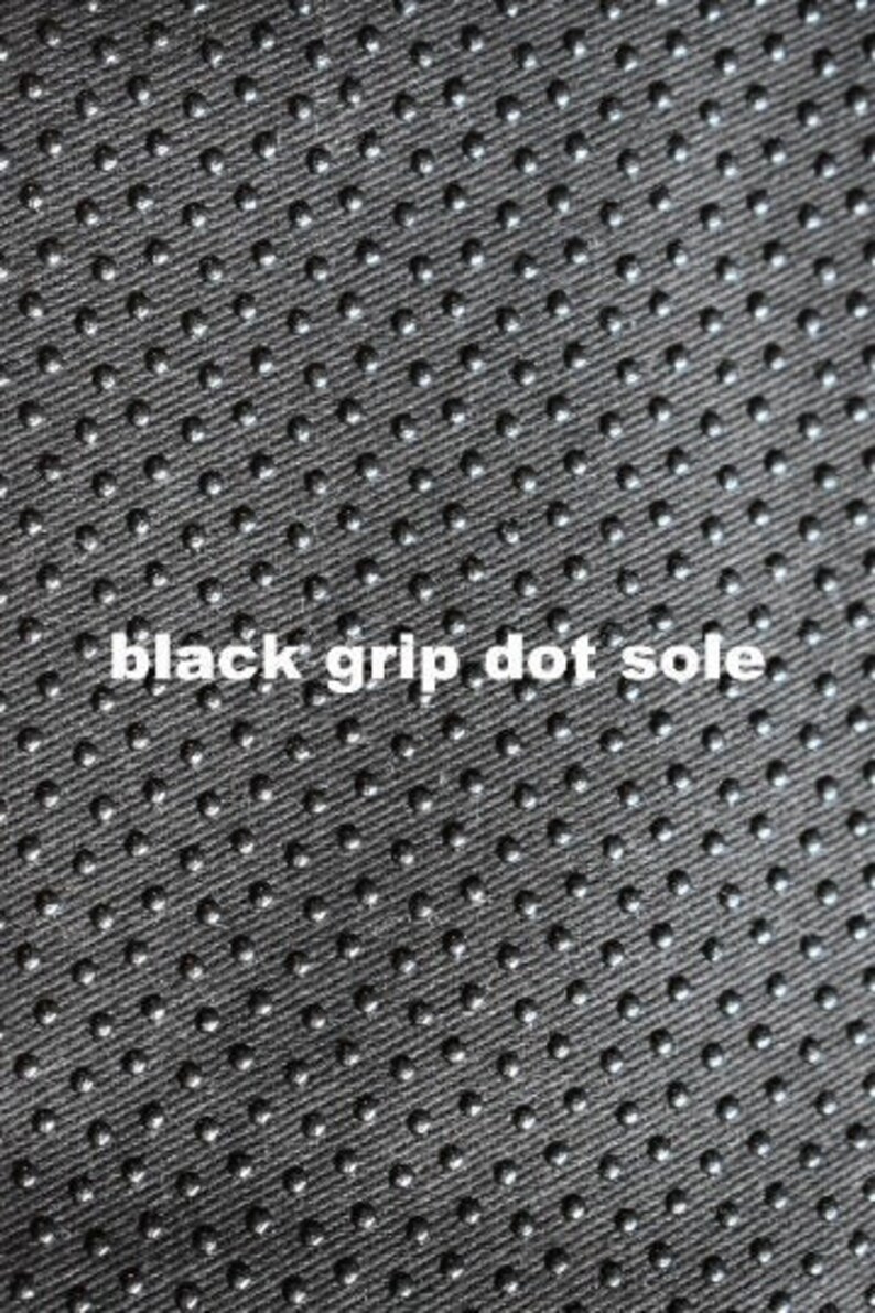 May include: Close-up of a black fabric with a pattern of small, raised dots. The fabric has a textured surface and is designed for grip.