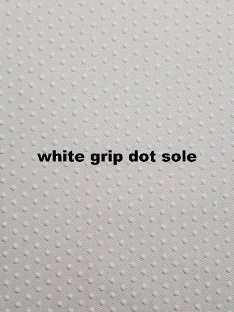 May include: White grip dot sole. The sole of a shoe or boot with a white, textured, dot pattern.