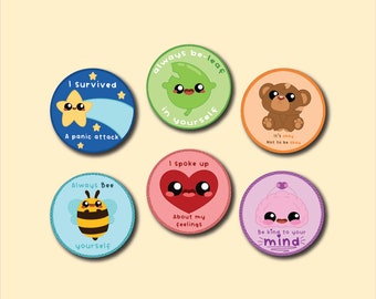 May include: Six colorful round stickers with cartoon characters and positive affirmations. The stickers feature a bee, a heart, a leaf, a bear, a star, and a cloud. The text on the stickers includes "Always Bee Yourself", "I Spoke Up About My Feelings", "Always Be-Leaf In Yourself", "It's Okay Not To Be Okay", "I Survived A Panic Attack", and "Be Kind To Your Mind".