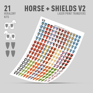 May include: A sheet of laser print transfers featuring various heraldic shield designs in red, blue, yellow, and black. The sheet includes the text "HORSE + SHIELDS V2" and "21 HERALDRY KITS". The shields are arranged in rows and columns.