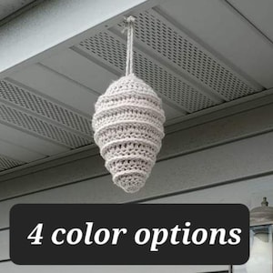 May include: A handmade, light beige crochet hanging decoration, shaped like a beehive. The item is suspended from a string and hangs from a white structure. The text "4 color options" is displayed on a black background.