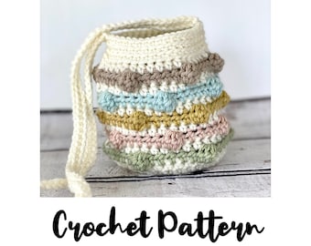 May include: A crocheted basket with a handle, featuring a multi-colored striped pattern in shades of beige, light blue, yellow, pink, and green. The basket is made with a textured stitch and has a crocheted handle.