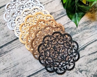May include: A set of six paper doilies in various shades of brown, from white to black, with intricate lace designs. The doilies are arranged in a fan shape on a wooden surface.