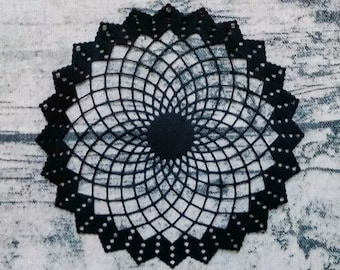 May include: Four decorative paper doilies in gold, silver, and brown with a black paper doily in the foreground. The doilies are all circular and have a geometric design. A gold ruler is also in the image.