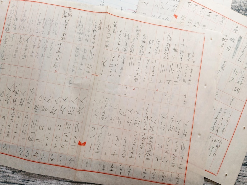 May include: A close-up of a handwritten document with a grid pattern and Japanese characters. The document is filled with mathematical equations and calculations.