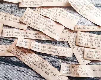 Könnte beinhalten: Eine Sammlung kleiner, rechteckiger Papierstücke mit handgeschriebenen Weihnachtsbotschaften. Die Botschaften sind in Schreibmaschinenschrift gedruckt und beinhalten Sätze wie "Lasst uns Weihnachten genießen, bis unsere Kreditkartenabrechnungen kommen" und "Es ist alles Spaß und Spiel, bis der Weihnachtsmann die Liste der Unartigen überprüft".