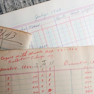 May include: Close-up of a vintage ledger with handwritten entries in red and black ink. The ledger is open to the month of November 1924 and includes the text "Nut Begins with Music Nov. 23 - 1924 Hulbutam. Erlange. org."