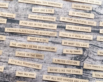 Könnte beinhalten: Eine Sammlung inspirierender Zitate, die auf braunen Papierstreifen gedruckt sind. Die Zitate beinhalten "Just One Life", "Find Joy in the Ordinary", "Make a Wish", "The Journey is the Destination", "Focus on the Good", "It's All Perspective", "Shine Like the Stars", "Not All Who Wander Are Lost", "Be Authentic", "Be Your Beautiful Self", "Own Your Dreams", "Lucky is a State of Mind", "Do What You Love", "In My Heart", "Limited Edition", "Life Doesn't Have to Be", "Life Was Meant", "Hold On", "Creative", "You Can Never", "Go +", "There is Beauty", "Use Your", "Best Day Ever".