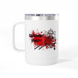 以下が含まれることがあります： シルバーの蓋とハンドルが付いた白いトラベルマグ。マグには、王冠をかぶったアライグマのグラフィック、血まみれの背景、黒い文字で「GODDAMNIT、DONUT！」が描かれています。
