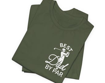 May include: Olive green t-shirt with the text "BEST Dad BY PAR" and a graphic of a golfer. The shirt is folded and has a classic crew neck design. The text and graphic are in white.