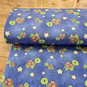 Könnte beinhalten: Blauer Stoff mit einem sich wiederholenden Muster aus grünen Schildkröten und gelben Sternen. Die Schildkröten haben braune Panzer und sind nach rechts gerichtet. Die Sterne sind fünfzackig und haben einen gelben Mittelpunkt.