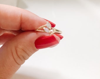 Puede incluir: Un anillo de oro con tres piedras ovaladas blancas engastadas en un diseño delicado.