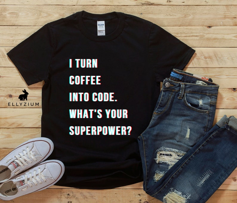 K&ouml;nnte beinhalten: Schwarzes T-Shirt mit wei&szlig;em Text, der "I turn coffee into code. What's your superpower?" lautet. Der Text ist in einer Glitch-Effekt-Schriftart.