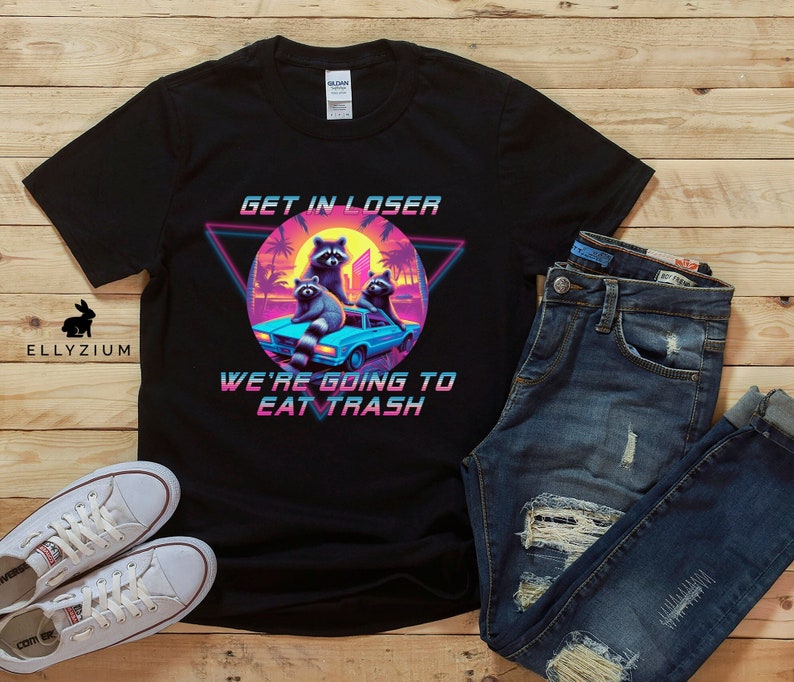May include: Black t-shirt with a retro 80s design featuring three raccoons in a car with the text "Get in loser, we're going to eat trash".
