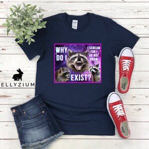 May include: A navy blue t-shirt with a graphic of three raccoons in a galaxy background. The text on the shirt reads "Why do I exist? I scream for I do not know."