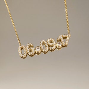 May include: Gold necklace with a date pendant featuring the numbers 06.09.17, each number is outlined with small clear stones.