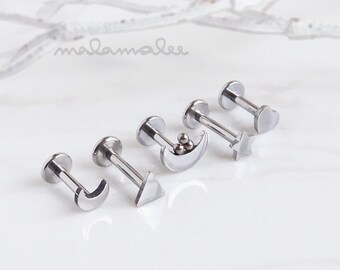 May include: Five silver body jewelry pieces with different designs. The designs include a crescent moon, a triangle, a crescent moon with three small balls, a star, and a heart.