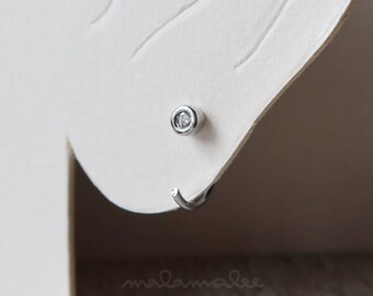 May include: A silver stud earring with a small, clear cubic zirconia stone.