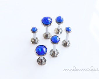 May include: A set of six blue opal body jewelry, each with a silver post and a round blue opal stone.
