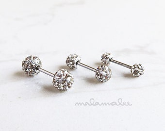 May include: Two pairs of silver barbell earrings with clear crystal balls. The balls are covered in small, clear rhinestones.