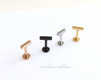 May include: Four different colored barbell earrings with a straight bar top. The earrings are gold, silver, black, and rose gold.