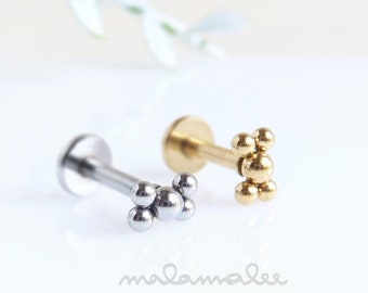 May include: Two small stud earrings with a cluster of tiny balls. The earring on the left is silver and the earring on the right is gold.