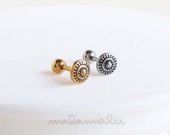 May include: Two silver and gold circular stud earrings with a textured design. The earrings are on a white surface.