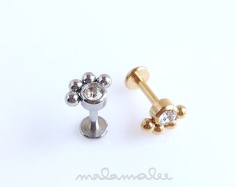 May include: Two surgical steel body jewelry pieces with a clear crystal and a cluster of small balls. One piece is silver and the other is gold.