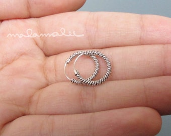 May include: A pair of silver hoop earrings with a twisted design. The earrings are small and delicate.