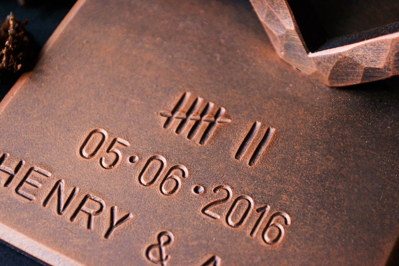 K&ouml;nnte beinhalten: Eine kupferfarbene Metallplakette mit dem Text "HENRY &" und dem Datum "05.06.2016" eingraviert. Au&szlig;erdem sind f&uuml;nf vertikale Linien und zwei horizontale Linien in die Plakette graviert.