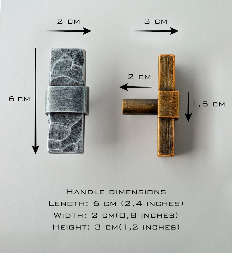 May include: Two cabinet handles are shown, one silver and one bronze. The silver handle is 6 cm (2.4 inches) long, 2 cm (0.8 inches) wide, and 3 cm (1.2 inches) high. The bronze handle is 6 cm (2.4 inches) long, 2 cm (0.8 inches) wide, and 1.5 cm (0.6 inches) high.