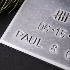 May include: A silver metal plaque with the text "PAUL &" and the date "06.15.20" engraved on it.