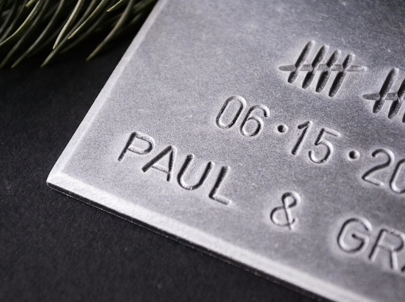 May include: A silver metal plaque with the text "PAUL &" and the date "06.15.20" engraved on it.