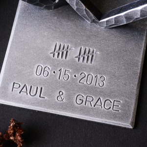 May include: A silver metal plaque with the date 06.15.2013, the names Paul & Grace, and a series of hash marks.