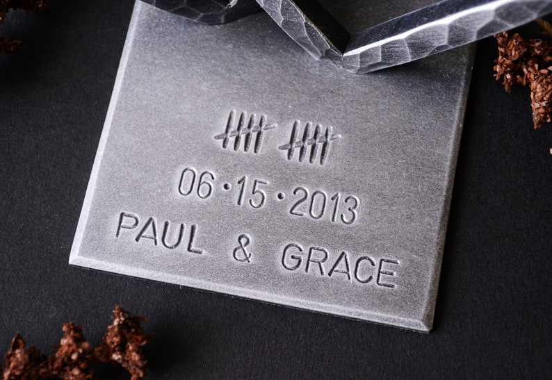 May include: A silver metal plaque with the date 06.15.2013, the names Paul & Grace, and a series of hash marks.