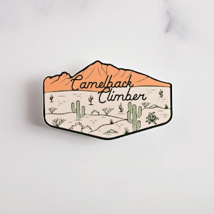 May include: A sticker with a desert landscape featuring a mountain range, cacti, and the text "Camelback Climber".
