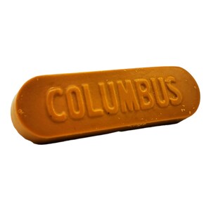 以下が含まれることがあります： 「COLUMBUS」という文字が浮き彫りになった茶色のワックスバー