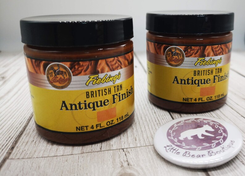 May include: Two brown glass jars with black lids containing Fiebings British Tan Antique Finish leather dye. Each jar contains 118 ml of dye.