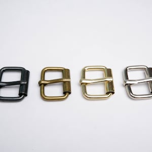 May include: Four metal belt buckles in different finishes: black, brass, gold, and silver.