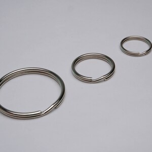 May include: Three silver key rings of different sizes. The key rings are made of metal and have a smooth finish.