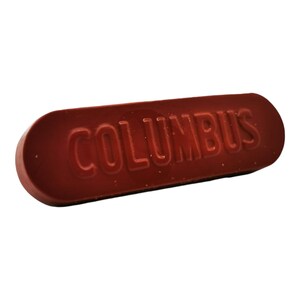 以下が含まれることがあります： 上面が「COLUMBUS」とエンボス加工された、赤色の長方形の靴磨きブロックです。