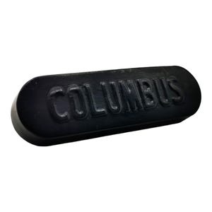 以下が含まれることがあります： 中央に「COLUMBUS」という文字が浮き彫りになった、黒色の楕円形の固形ワックスシールです。