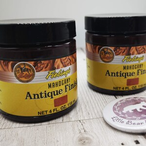 May include: Two 118 ml bottles of Fiebing's Mahogany Antique Finish leather dye. The bottles are brown with yellow labels and feature a horse and rider logo. The text on the label reads "Fiebing's Mahogany Antique Finish" and "Net 4 fl. oz. 118 ml".