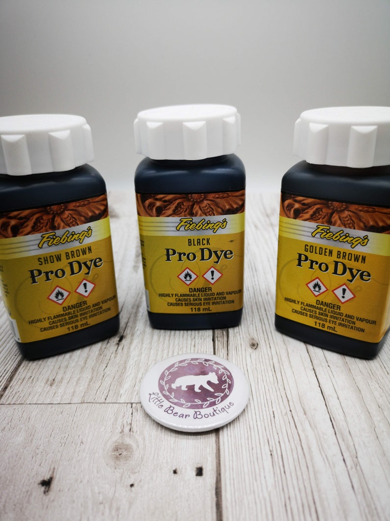 May include: Three glass bottles of Fiebing's Pro Dye leather dye. The bottles are labeled with the colors: Show Brown, Black, and Golden Brown. Each bottle contains 118 ml of dye.